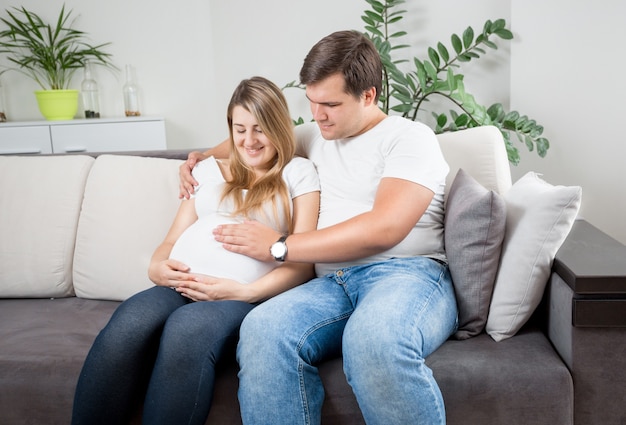 Photo gros plan de l'heureux couple attend bébé détente sur canapé