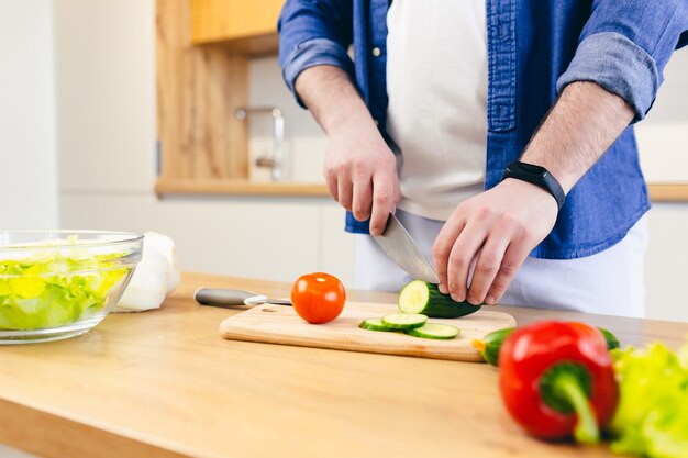 Photo gros plan un homme à la maison hache les légumes dans la cuisine prépare le petit déjeuner