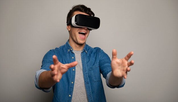 Photo en gros plan d'un homme surpris dans des lunettes VR, qui écarte les mains devant la caméra.