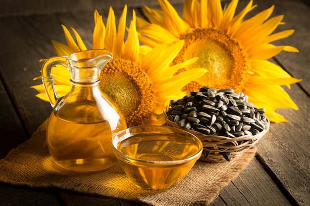 Photo gros plan de l'huile de tournesol avec des graines sur fond de bois. Concept de produit bio et biologique.