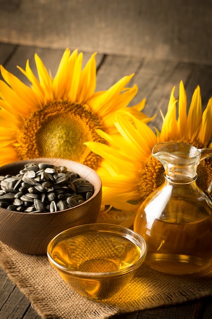 Photo gros plan de l'huile de tournesol avec des graines sur fond de bois. Concept de produit bio et biologique.