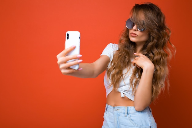 Photo gros plan de l'incroyable belle jeune femme blonde tenant un téléphone mobile prenant selfie photo à l'aide