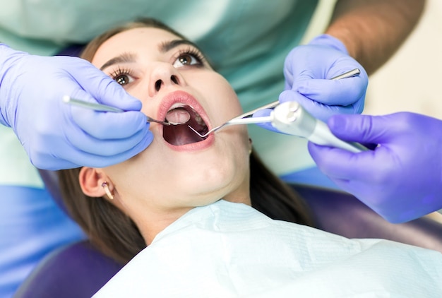 Photo en gros plan d'une jeune femme assise sur la chaise du dentiste avec la bouche ouverte au bureau du dentiste