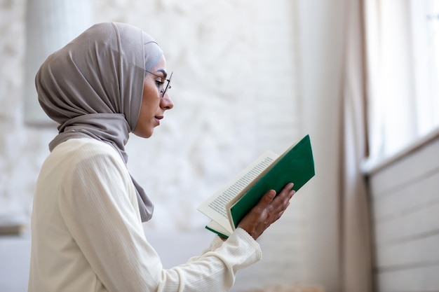 Photo gros plan une jeune femme dans un hijab et des lunettes tenant un livre saint vert dans ses mains la plia