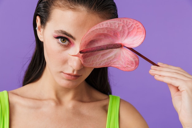 Photo gros plan d'une jeune femme de mode avec un maquillage lumineux tenant une fleur exotique