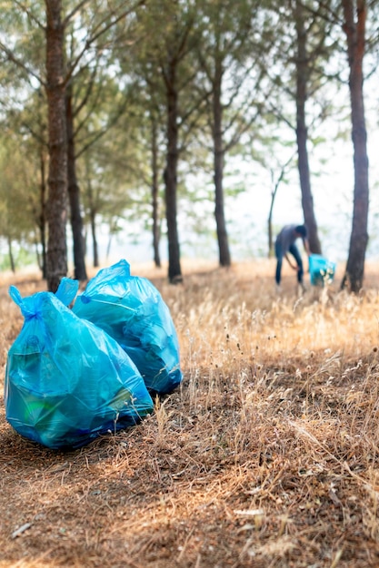 La photo en gros plan d'un jeune homme ramassant des déchets dans la forêt