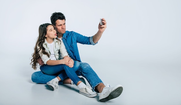 Photo en gros plan d'un jeune papa et de son petit enfant, qui s'embrassent tendrement et sourient, tout en regardant ensemble l'appareil photo.