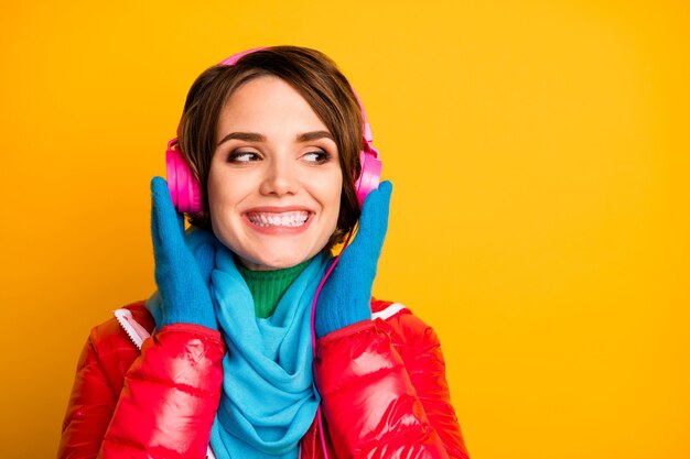 Photo gros plan de la jolie dame excitée écouter des écouteurs modernes à la recherche d'un espace vide porter des gants de foulard bleu pardessus rouge décontracté élégant