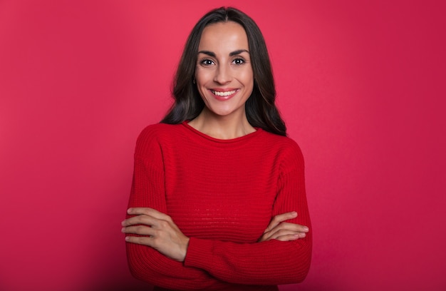 Photo en gros plan d'une jolie femme vêtue d'un pull rouge rubis, qui regarde dans l'appareil photo