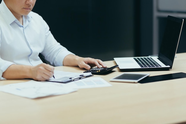 Une photo en gros plan d'une main d'homme d'affaires travaillant sur la paperasse qu'un comptable calcule