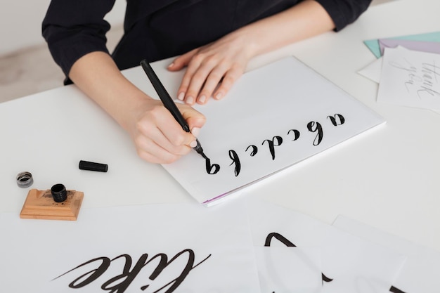 Photo en gros plan de mains de jeune femme écrivant l'alphabet sur papier sur le bureau isolé