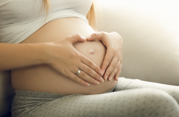 Photo gros plan d'une mère attentionnée enceinte touchant le ventre