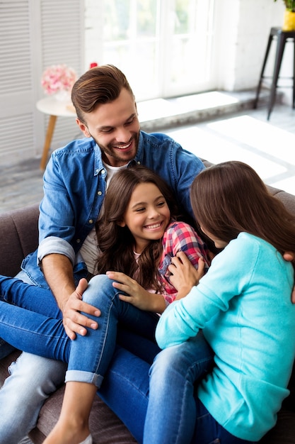 Photo en gros plan de la mère, du père et de leur fille posant ensemble pour une photo commune dans leur salon élégant, s'embrassant avec des sourires radieux