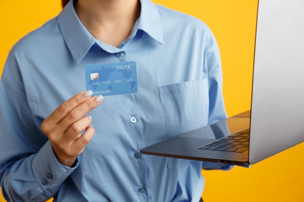 Photo gros plan d'ordinateur portable et carte de crédit d'achat dans les mains de la femme.