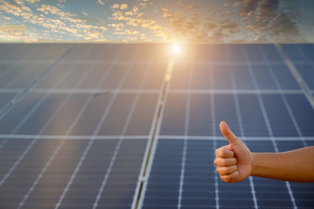 Une photo en gros plan pose un geste positif sur un panneau solaire photovoltaïque Sur le toit de la maison et avec un coup de pouce ou comme des idées d'économie d'argent et d'énergie propre.