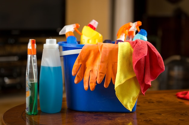 Photo en gros plan de produits chimiques de nettoyage, de gants et de chiffons se trouvant dans un seau en plastique