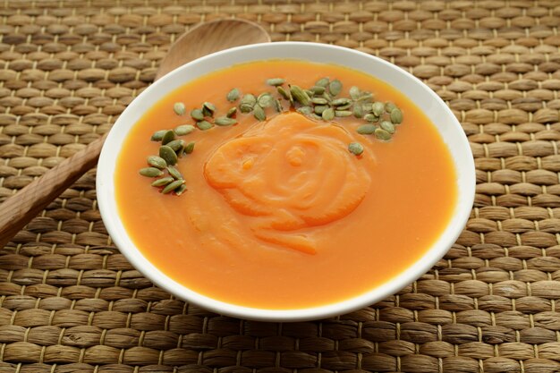 La photo en gros plan de soupe de potiron en purée avec des graines de citrouille sur la table