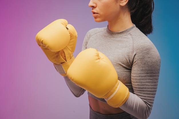 La photo en gros plan de la sportive forte en gants de boxe boxeur posant