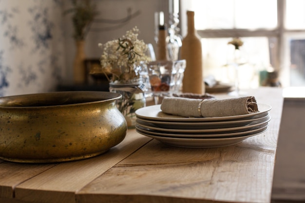 Photo en gros plan d'une table en bois avec des assiettes en porcelaine, une serviette en papier et un récipient en cuivre