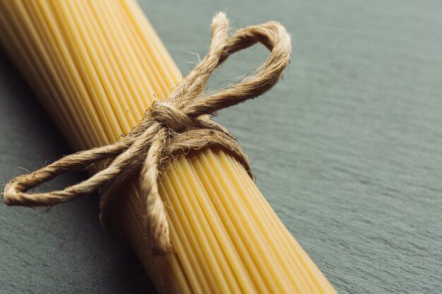 La photo en gros plan d'un tas de spaghettis crus attachés avec une corde. Espace de copie sur le côté droit