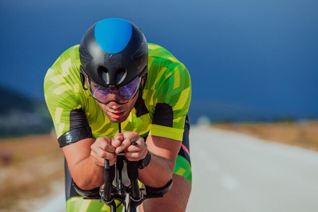 Photo en gros plan d'un triathlète actif en tenue de sport et avec un casque de protection faisant du vélo. Mise au point sélective.