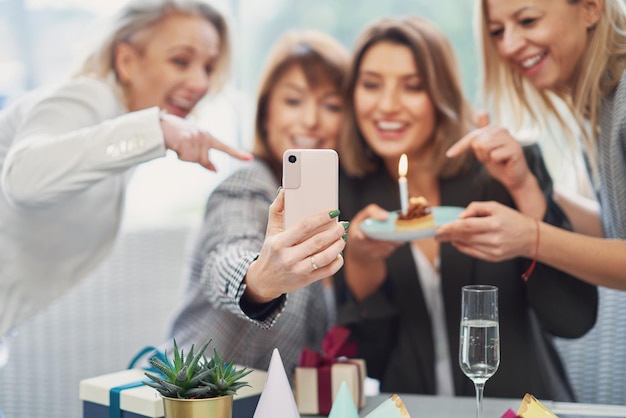 Photo d'un groupe de filles avec un gâteau d'anniversaire prenant un selfie