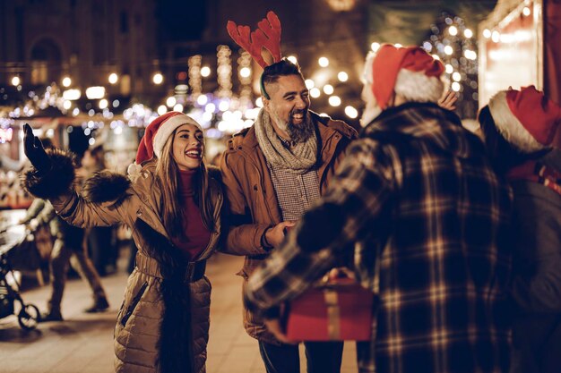 Photo d'un groupe de jeunes amis joyeux avec des cadeaux de Noël s'amusant lors d'une soirée.