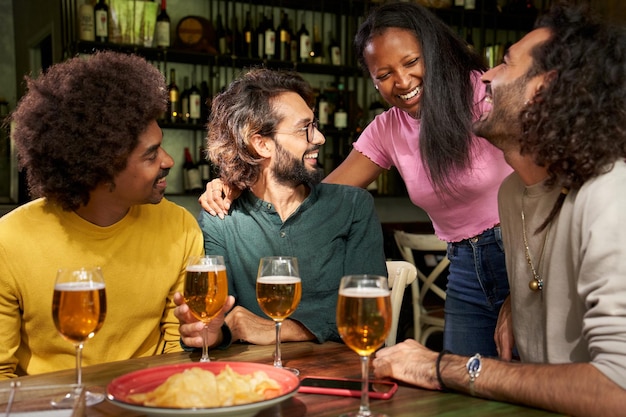 Photo photo de groupe multiraciale d'amis souriants rassemblés au restaurant-bar après le travail au pub happy hour