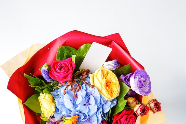 Photo d'en haut bouquet de roses multicolores avec carte sur fond blanc vide