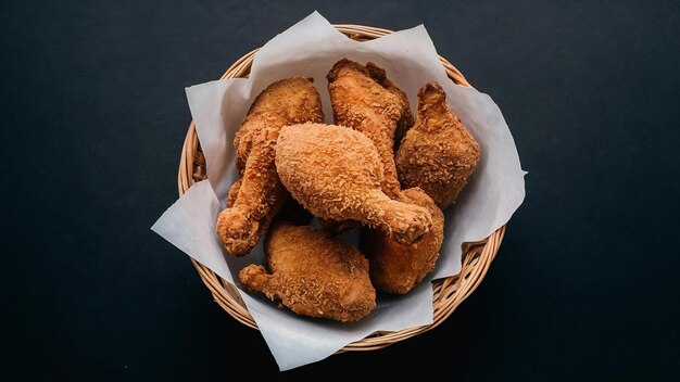 Une photo haute angle d'un panier de poulet frit délicieux sur une surface noire