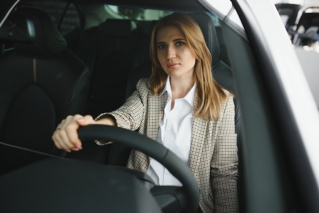 Photo de l'heureuse jeune femme assise à l'intérieur de sa nouvelle voiture. Concept pour la location de voitures