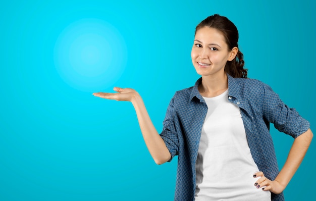 Photo de heureuse jeune femme debout, regardant la caméra montrant la surface pointée