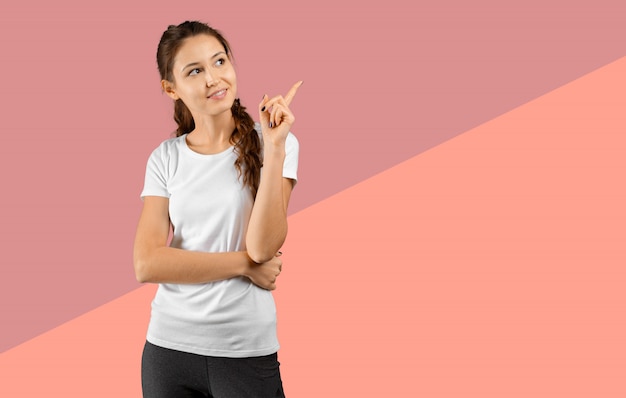 Photo de heureuse jeune femme debout, regardant la caméra montrant la surface pointée