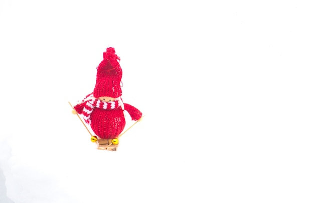 Photo d'hiver avec des décorations de Noël pour sapin. Fille de jouet bonhomme de neige tricoté debout sur le ski dans la forêt. Carte postale d'ornements de joyeuses fêtes. Temps de neige.