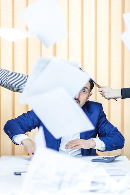 Photo d'un homme d'affaires en costume bleu ayant beaucoup de travail assis au bureau
