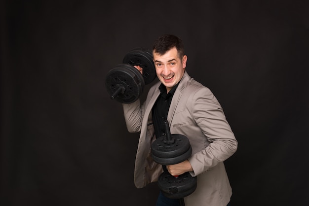 Photo d'homme d'affaires détenant des haltères, concept de puissance métallique d'entreprise, debout sur fond gris