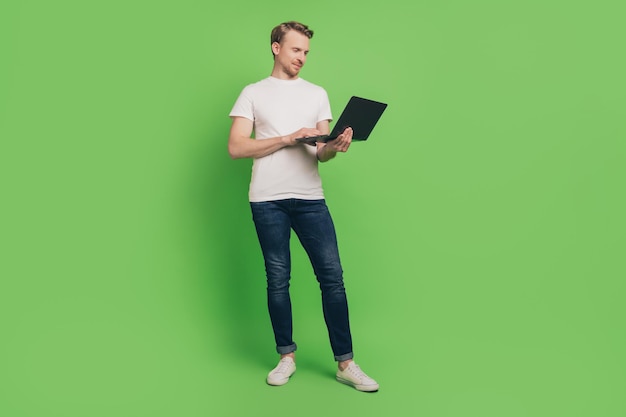 Photo d'un homme d'affaires indépendant confiant tenir un bogue de code de saisie de netbook portant un t-shirt blanc sur fond de couleur verte
