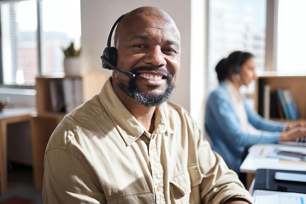 Photo d'un homme d'affaires mature utilisant un casque dans un bureau moderne avec son collègue travaillant en arrière-plan