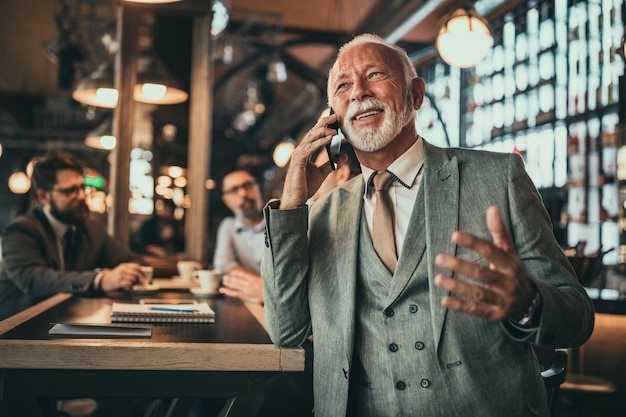 Photo d'un homme d'affaires senior parlant au téléphone dans le pub