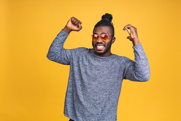 Photo d'un homme afro-américain noir ravi sachant qu'il est devenu le gagnant de quelque chose de si réjouissant en profitant des informations d'actualité tout en étant isolé sur fond jaune.