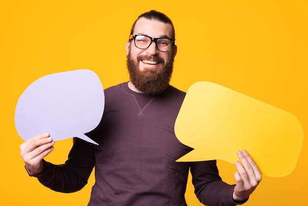 Photo d'un homme à la barbe portant des lunettes tient deux bulles