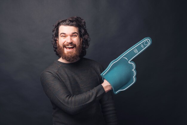 Photo d'un homme avec barbe tient un gant de ventilateur pointant vers un espace libre excité est à la recherche