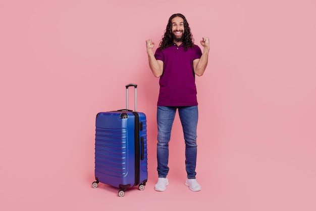 Photo d'un homme étonné se réjouir de la meilleure variante de voyage à l'étranger porter un t-shirt violet isolé sur fond de couleur rose