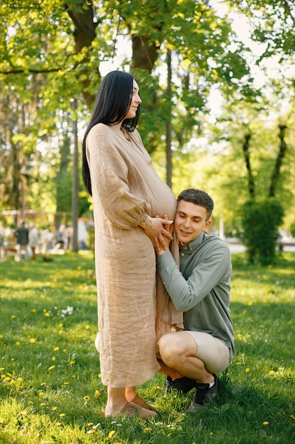 Photo d'un homme étreignant le ventre enceinte de sa femme alors qu'il se tenait dans le parc