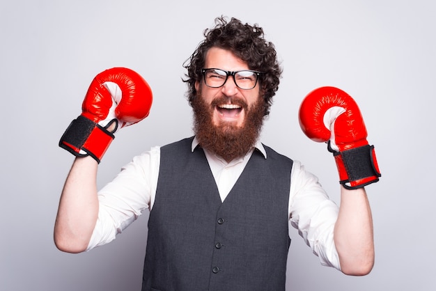 Photo d'un homme portant un costume et des gants de boxe célébrant et criant