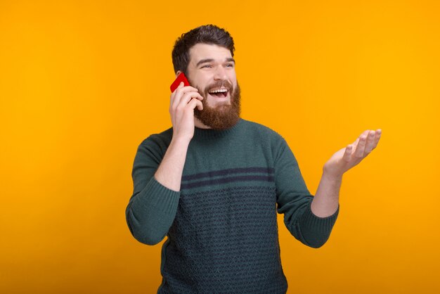 Photo d'un homme positif parlant au téléphone et faisant des gestes.