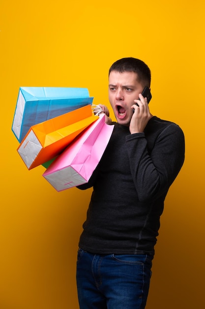 Photo d'un homme shopper avec des sacs en papier carte bancaire et téléphone à la main