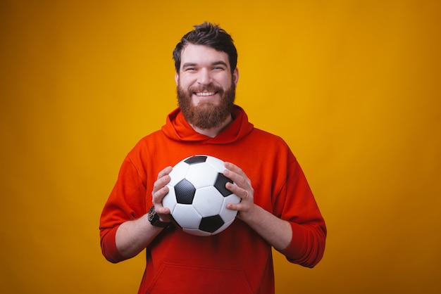 Photo d'un homme souriant tient un ballon de football ou de soccer et montre le pouce vers le haut ou comme un geste.