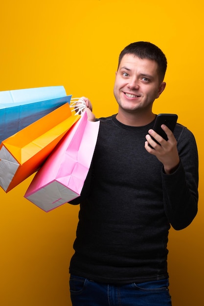 Photo d'un homme avec un téléphone et des sacs à provisions multicolores