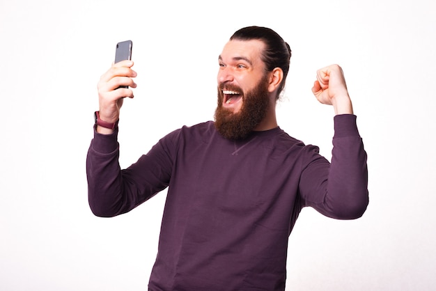 Photo d'un homme tenant un téléphone en le regardant et étant très excité